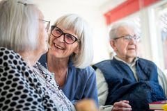 Ældre kvinde smiler og taler med en person i en plejebolig.