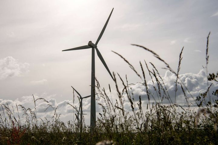 To vindmøller i en mark under overskyet himmel.