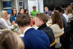 Gruppe unge mennesker sidder samlet omkring et bord til møde.