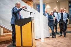 Borgmester holder tale ved podiet, mens flere mænd lytter i baggrunden på Rådhuset.