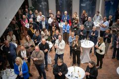 Gruppe af mennesker står ved høje borde og klapper under en nytårskur.