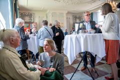 En gruppe mennesker deltager i en sammenkomst i en elegant sal ved Schackenborg Slot.