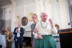 Jeg ved ikke, hvem der er på billedet, men her er et forslag til alt-tekst:

"Ældre kvinde modtager støtte fra yngre kvinde, mens publikum klapper."