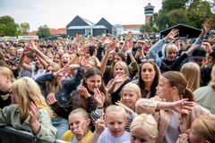 En stor forsamling af glade mennesker deltager i en udendørs begivenhed.