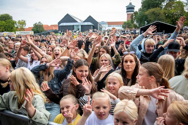 En stor forsamling af glade mennesker deltager i en udendørs begivenhed.