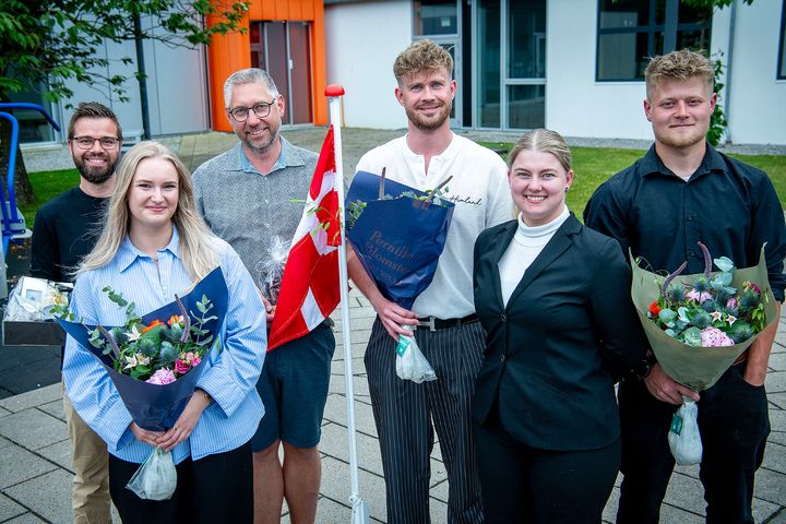 Gruppefoto af prisvindere ved Fest for Fremtidens Faglærte med blomsterbuketter.