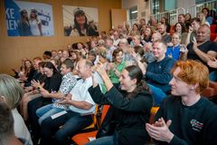 En gruppe mennesker sidder i et auditorium og klapper under en begivenhed.