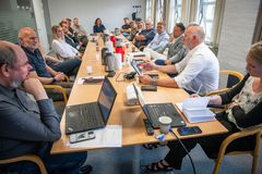 En gruppe mennesker sidder omkring et bord i et mødelokale.