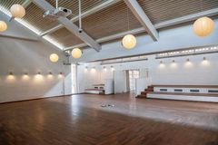 Lys og renoveret mødesal med træloft og kuglelamper.
