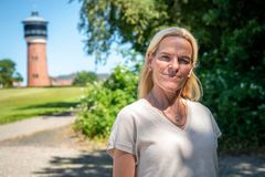 En kvinde står udendørs med et tårn i baggrunden.