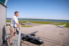Mand kigger ud over en lufthavn med flere fly på landingsbanerne i baggrunden.