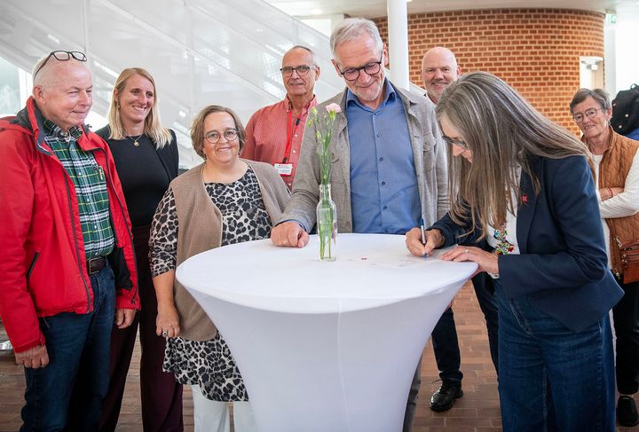 En gruppe mennesker står omkring et bord, mens to personer underskriver en aftale for at forbedre beredskabet, omkranset af Røde Kors- og Tønder Kommune-repræsentanter.