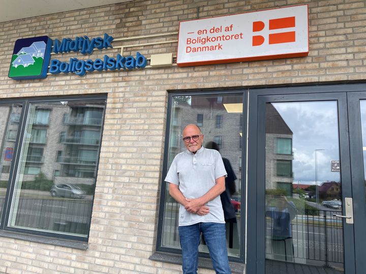En mand står foran bygningen til Midtjysk Boligselskab.