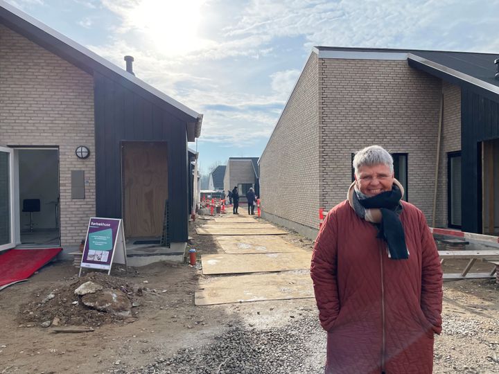 En person i en rød frakke står foran nybyggede huse ved et åbent hus arrangement i Rørbækhus.