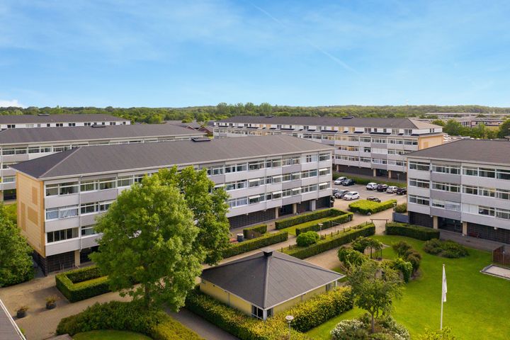 Luftfoto af en boligblok i Kolding Nord med grønne områder og parkeringspladser.