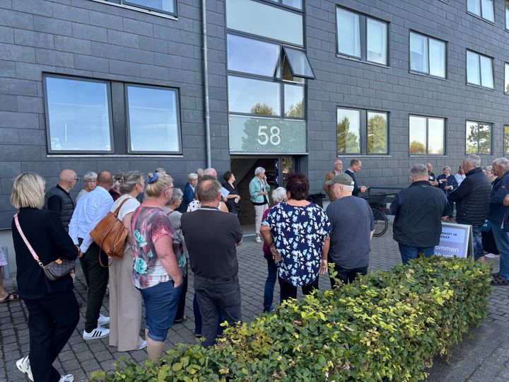 En gruppe mennesker står uden for en bygning under et åbent hus-arrangement.