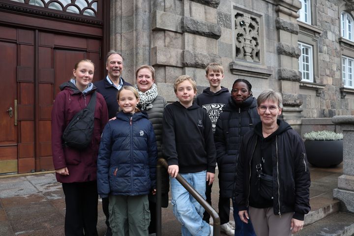 En gruppe børn og voksne står foran indgangen til Christiansborg.