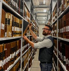 Chefkonsulent og projektleder for Multigenerationsregistret, Jeppe Klok Due, er gået ned i Rigsarkivets magasiner, hvor der står lange rækker af de kirkebøger, der udgør kernen i projektet.