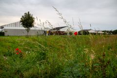 I forgrunden nogle røde valmuer og højt græs, i baggrunden et af de tørre bassiner og boliger allerbagerst