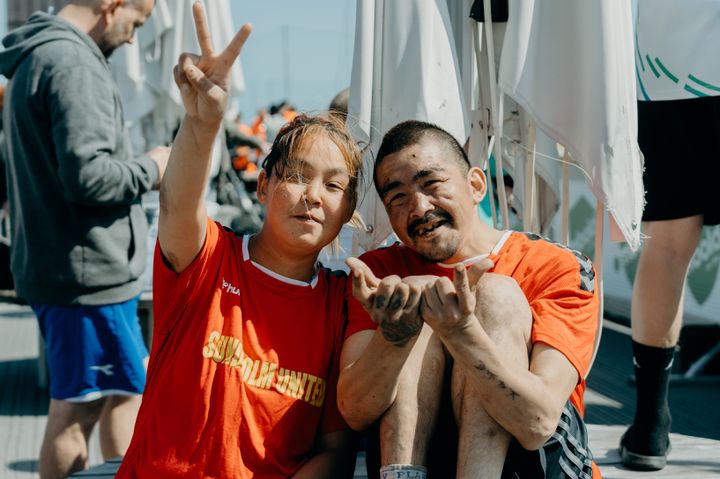 To smilende spillere fra Sundholm ved OMBOLD-stævne, iført orange T-shirts.