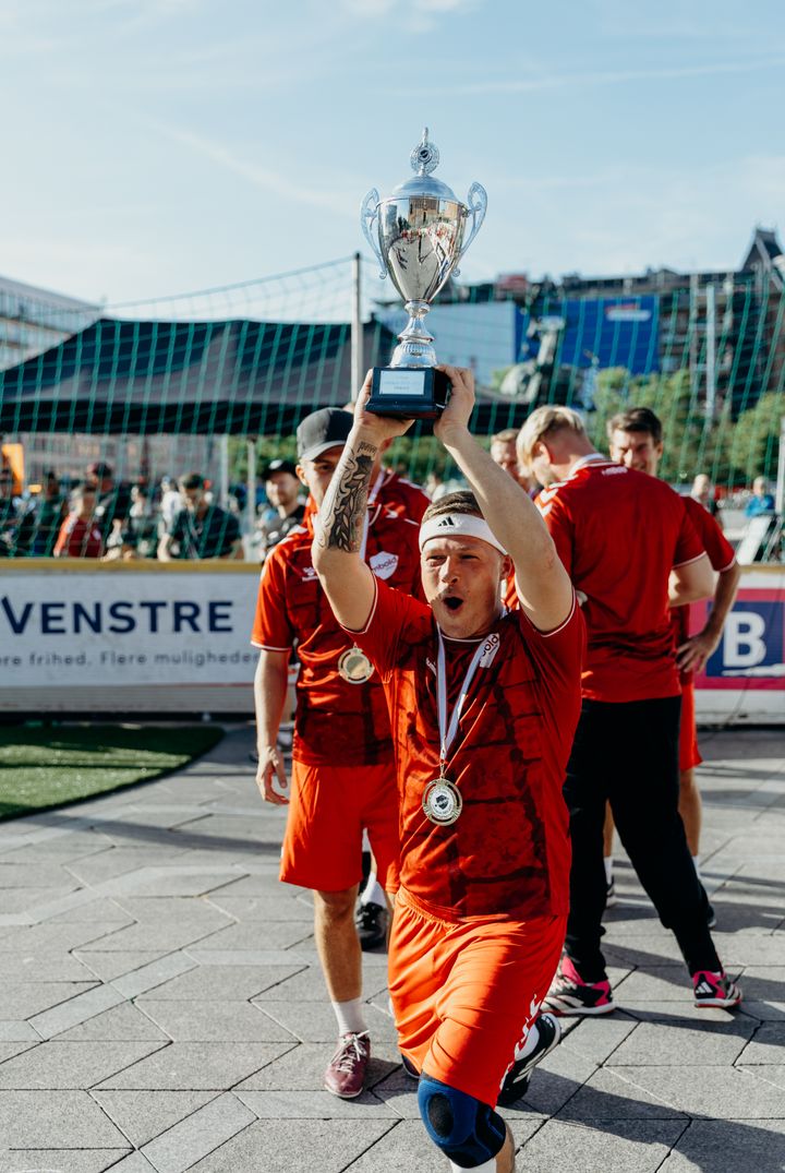 Anfører for hjemløselandsholdet løfter pokal
