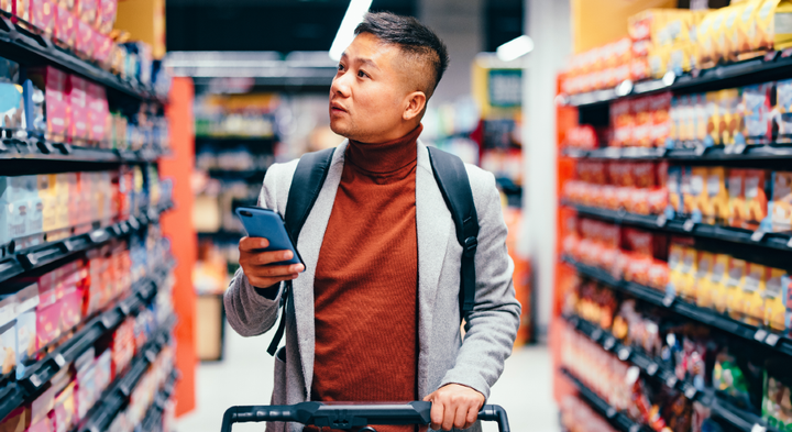 forbruger med smartphone i et supermarked