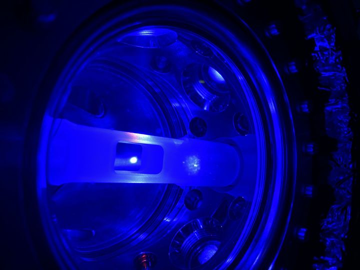 Her ses en MOT "Magneto-optical trap”, som forskerne har brugt til at måle tiden. Den lysende bold i midten består af cirka 300 millioner strontiumatomer svævende frit i et vakuumkammer nedkølet til det absolutte nulpunkt. Foto: Eliot Bohr