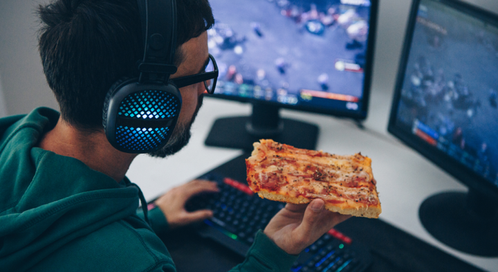 Man eating pizza and gaming