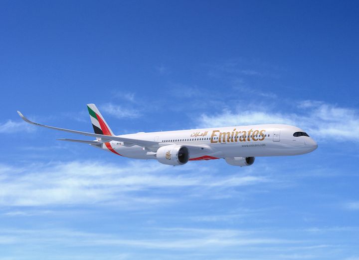 Emirates Airbus A350-900 flyver i blå himmel med lette skyer.