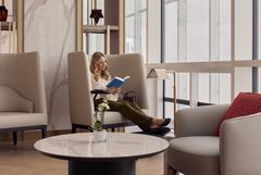 Billedet viser en kvindelig kunde i et roligt afslapningsområde i Emirates’ lounge i München.