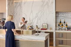 Billedet viser en kvindelig kunde i samtale med en mixolog i Emirates’ lounge.