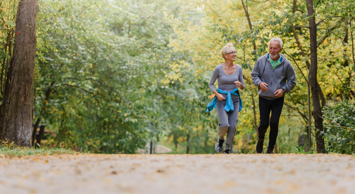 Ældre par jogger i en grøn park.