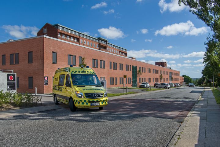 Regionshospitalet Randers fotograferet i dagslys. En ambulance ses forlade hospitalet.