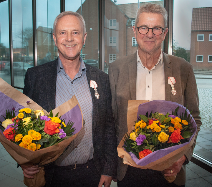 Regionsrådsmedlemmerne Ib Bjerregaard (tv) og Morten Flæng med Dannebrogordenens Ridderkors i reverst og blomsterbuketter i hænderne.