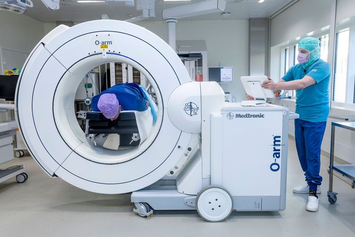Billedet viser en patient, der ligger i en medicinsk scanner under vejledning af en sundhedsmedarbejder.