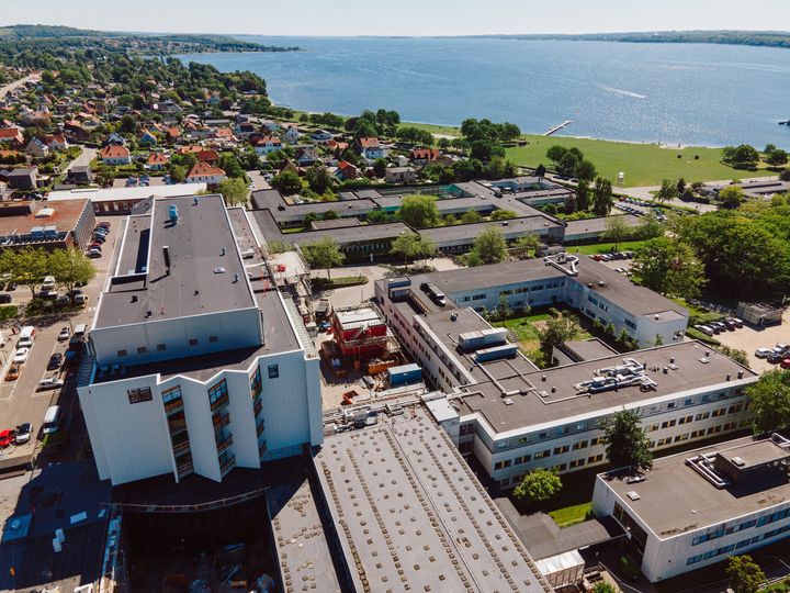 Luftfoto af Regionshospitalet Horsens med boliger og kystlinje i baggrunden.