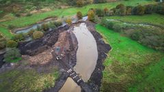 Luftfoto af et område ved Vejle Å, hvor genslyngningsprojektet finder sted, med synlige gravedigter og vandløb omgivet af grønt landskab.