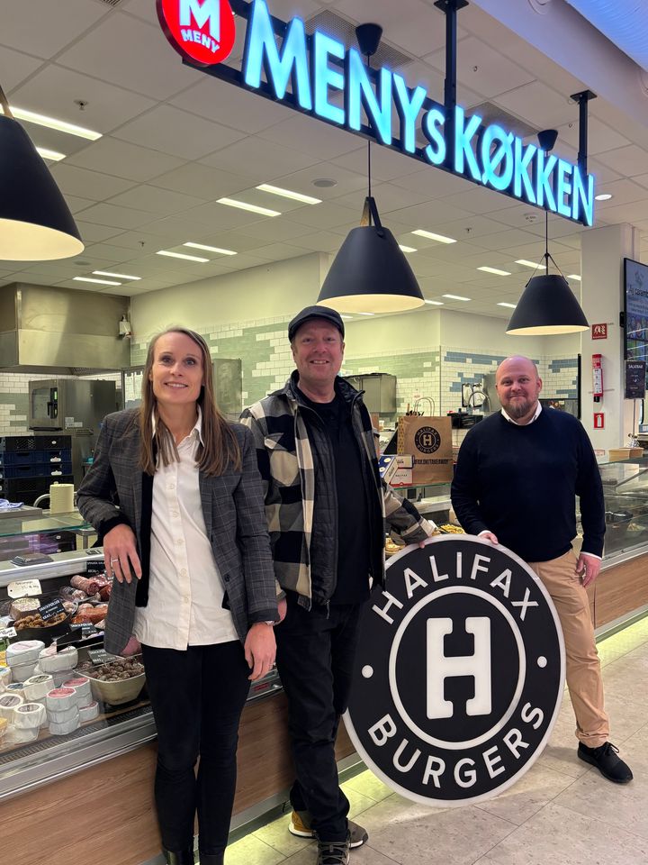 Er du sulten efter burger, kan du glæde dig til Halifax-burgere i udvalgte MENY-butikker. Kommerciel direktør i MENY, Kristine Pilgaard og kædedirektør Richo Boss flankerer her Peter Bækbro Ahn, medstifter af Halifax Burgers, i MENY Domus Vista, som bliver den første butik med burgerne.