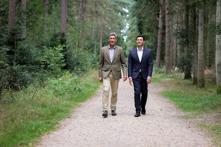 To personer i jakkesæt går på en skovsti.