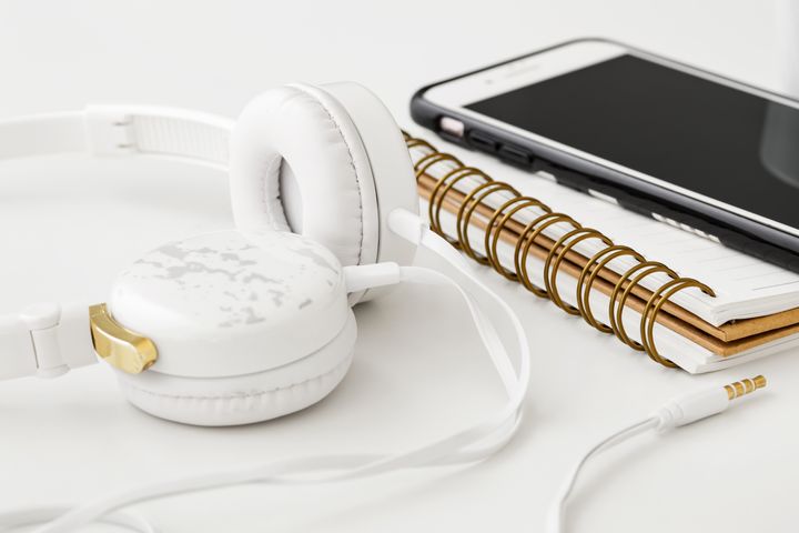 Alt tekst: Hovedtelefoner, notesbog og smartphone på et skrivebord.