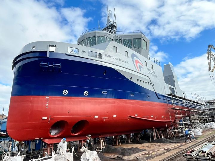 Et stort OSSV-skib i blå, grå, og rød maling ses på værft.