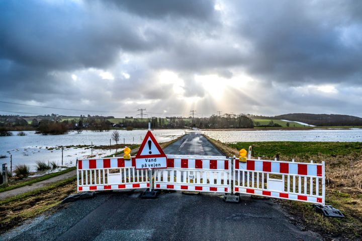 En vejbom afspærrer landevejen, som er oversvømmet af vand efter en storm.