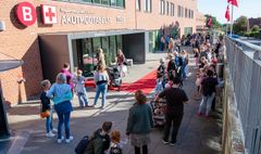 En lang kø af mennesker uden for en hospitalsindgang med skiltet "Akutmodtagelse".