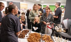 Gruppe mennesker nyder snacks ved et arrangement på et hospital.