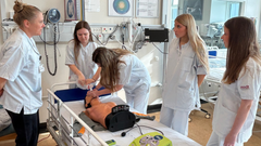 Uddannelsesansvarlig sygeplejerske Trine Kvist-Hofmann viser praktikanterne, hvordan man anvender hjertestopudstyr til basal hjertestop træning.