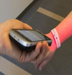 Billedet viser, hvordan QR-koden på patientens armbånd nemt scannes med en smartphone.