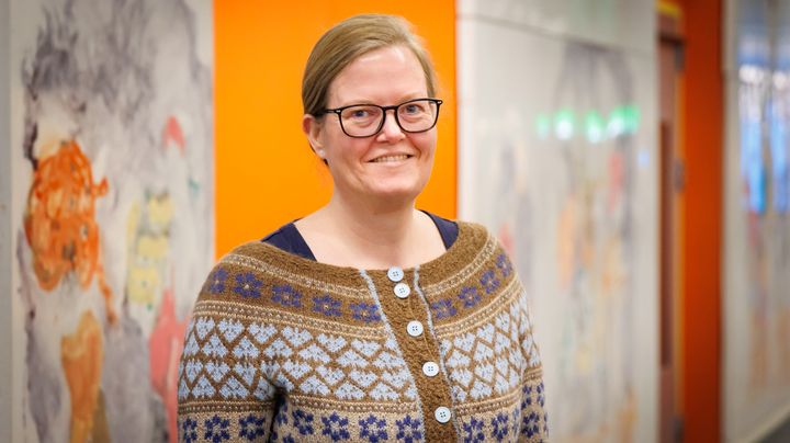 Portræt af kvinde foran kunstværk.