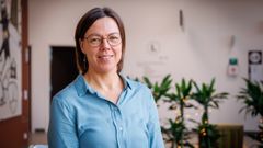 Portræt af kvinde med briller og i blå bluse.