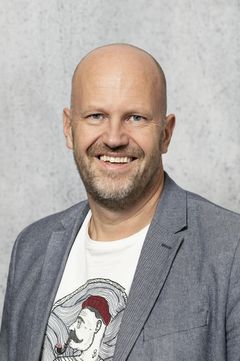 Mand i gråt og hvidt kontortøj på grå baggrund.