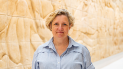 Kvinde i lys bluse med lyst kunstværk i baggrunden.